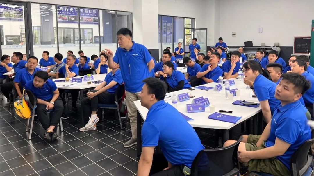 身着蓝色培训服的教师在汽车实训教室交流